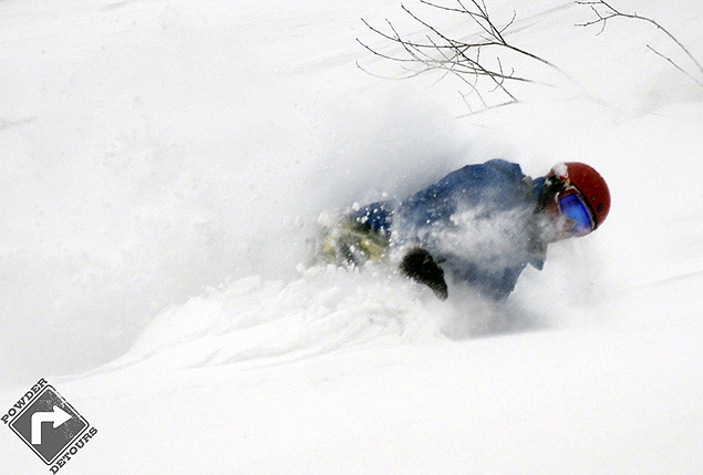 Bob laying over a toe-side in the pow - Powder Detours