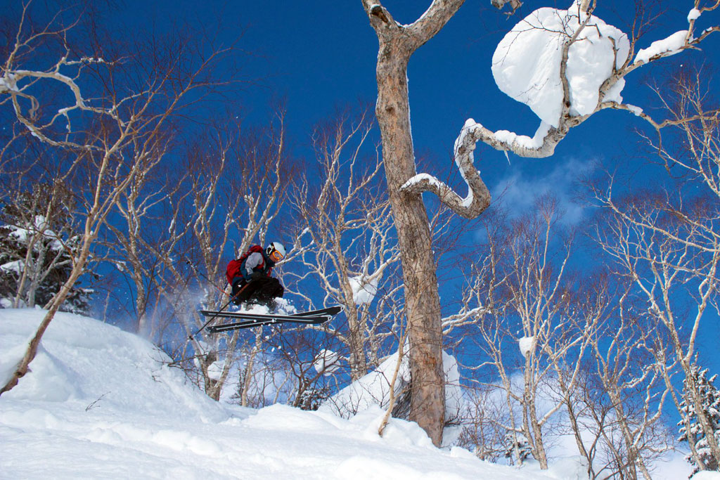 skier jumping in powder at Kiriro - powderdetours.com